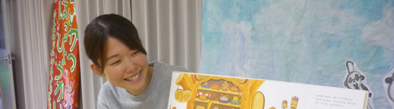 写真：カーテンの前に座り絵本を読み聞かせする先生2