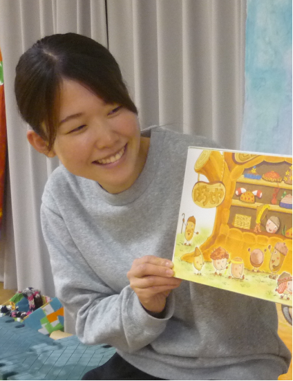 写真：カーテンの前に座り絵本を読み聞かせする先生