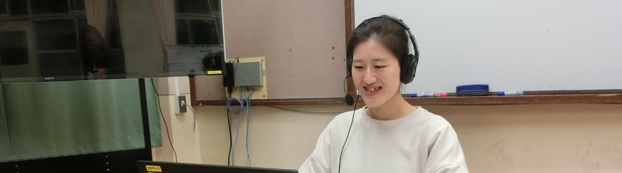 写真：パソコンの前に座るヘッドフォンをした女性2