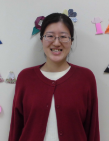 写真：折り紙で飾られた壁の前に立つ女性