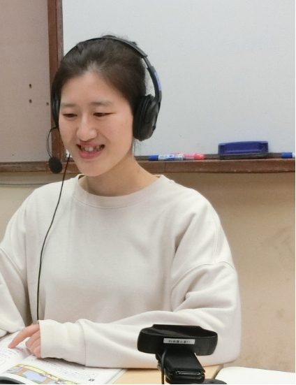 写真：パソコンの前に座るヘッドフォンをした女性